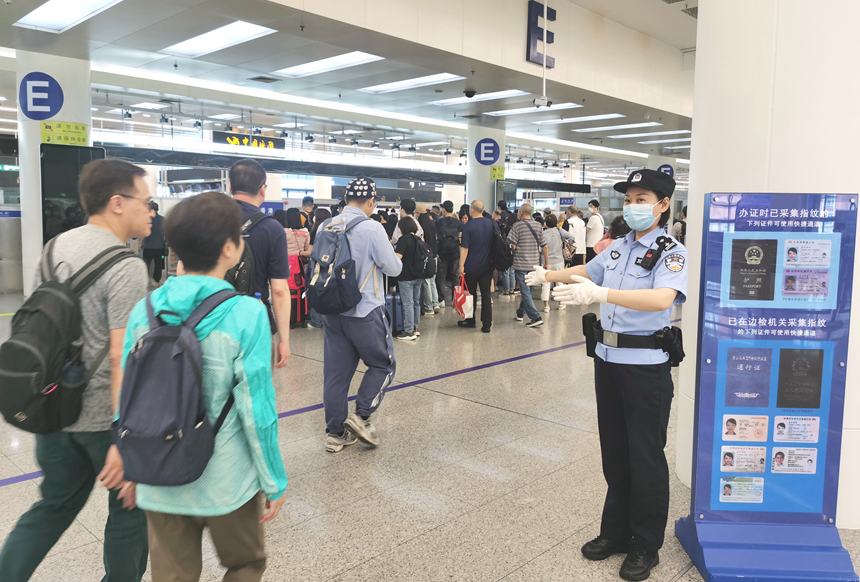 皇岗边检站民警在福田口岸出境大厅引导旅客有序快速通关。黄俊生摄